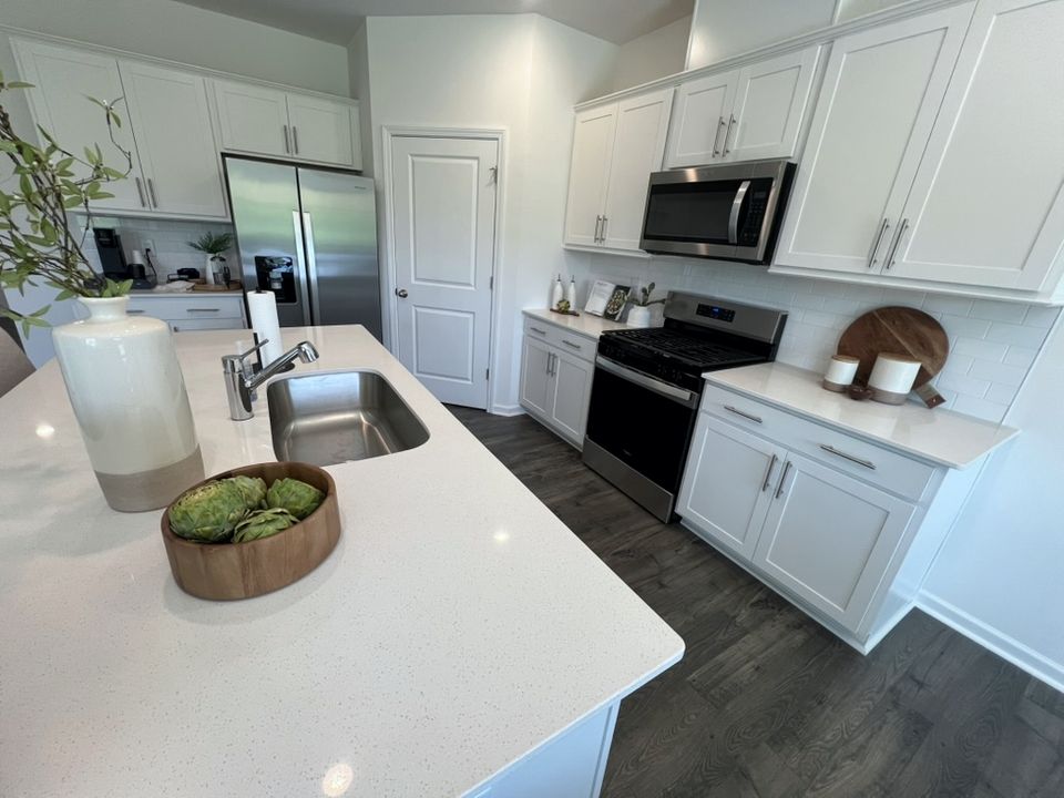 Kitchen in the Hayden model: white cabinets, quartz countertops, stainless gas range