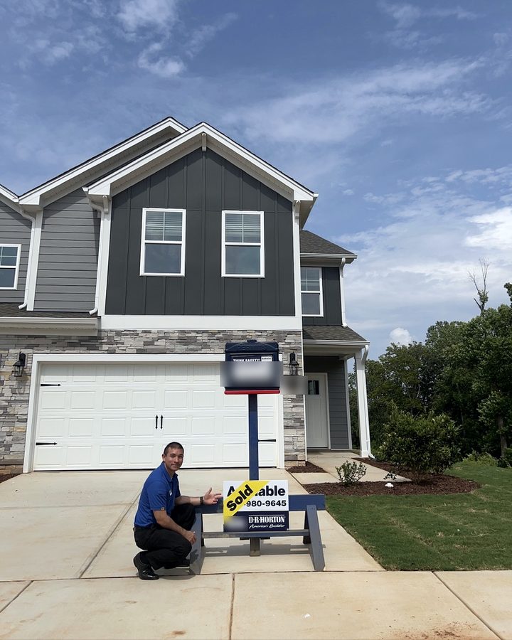 Charles beside a sold sign at a finished Collins Ridge home