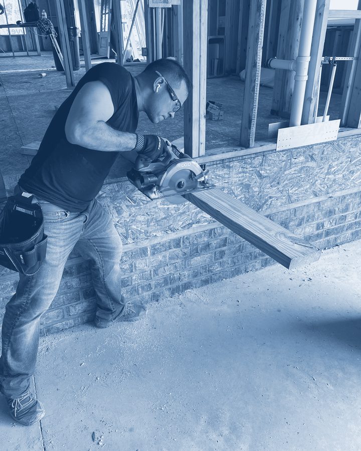 Charles cutting lumber on a framed house